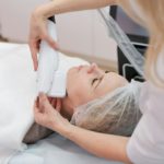 Beautician makes cute caucasian woman facial vacuum treatment for rejuvenation.